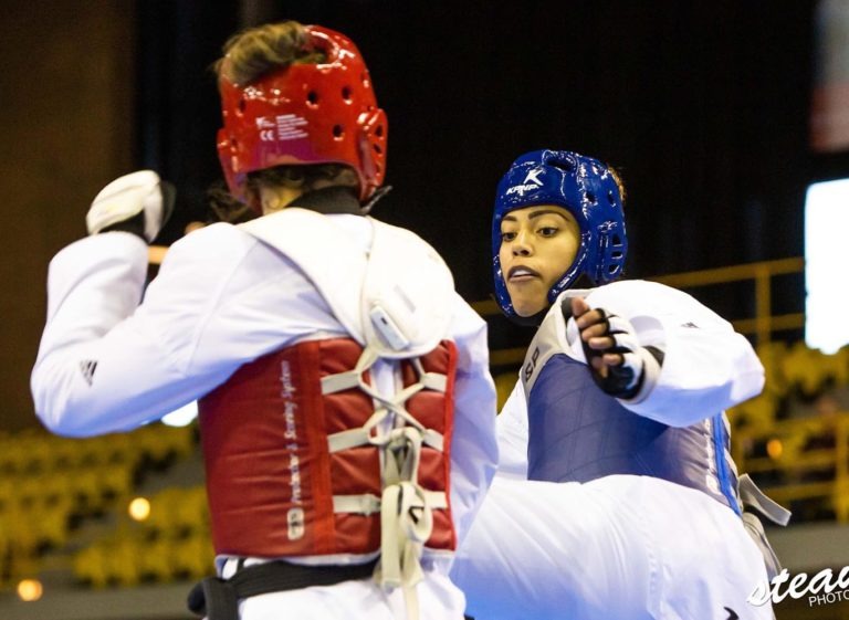 Two elite athletes engaging in an intense match using an electronic scoring system and professional head guards for maximum safety.