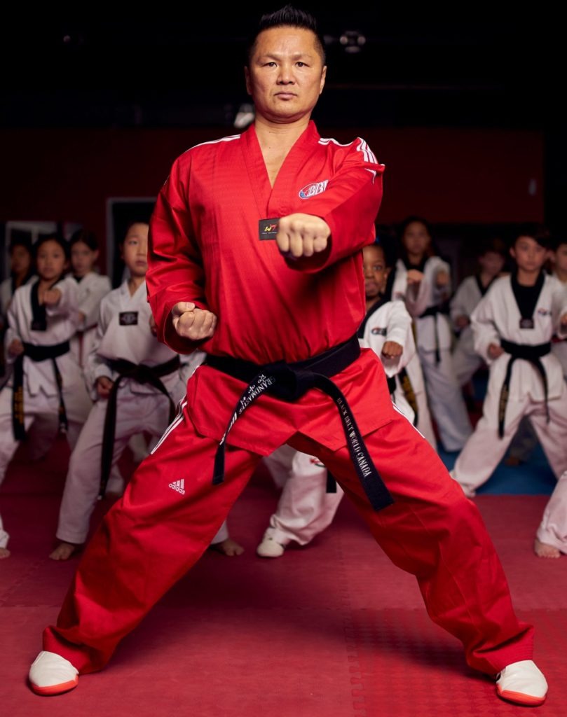 A high-ranking martial artist demonstrating traditional poomsae forms while teaching students the core values of dojo discipline and focus.