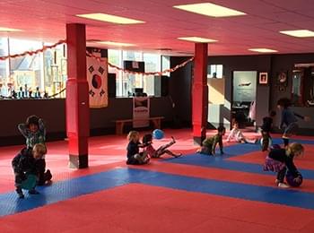 Children celebrating with rainbow cake during a taekwondo themed party at a local martial arts school.