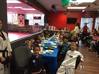 Young students enjoying a birthday party in a martial arts school lounge to celebrate team building.