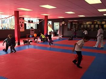 Young students practicing taekwondo striking drills on professional martial arts mats to build confidence.